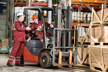 warehouse workers in front of forklift - obrazy, fototapety, plakaty