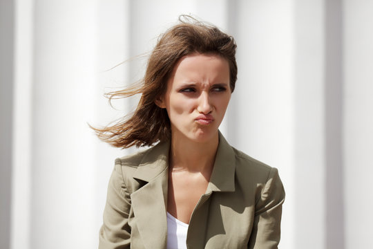 Angry young woman against a white wall