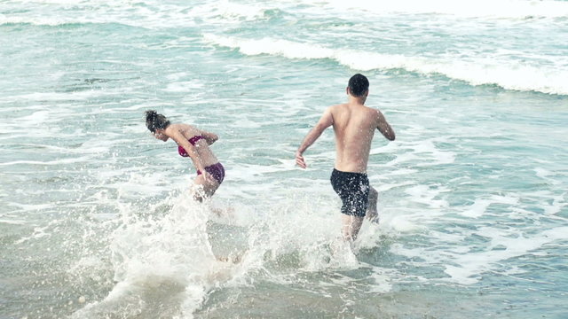 Happy couple playing in the sea, slow motion shot at 240fps