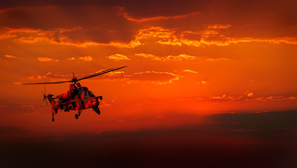 Fototapeta na wymiar Wojskowy śmigłowiec w locie przed dramatyczną czerwone niebo