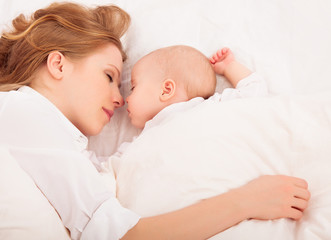 mother embraces the newborn baby  sleeping together in bed © JenkoAtaman
