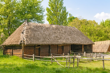 Fototapeta na wymiar A typical antique Ukrainian wooden country house or farm with a thatch roof, in the countryside near Kiev 