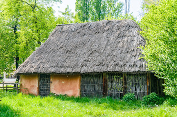 Fototapeta na wymiar A typical antique Ukrainian country house with a thatch roof, in the countryside near Kiev 