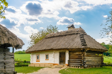 Fototapeta na wymiar A typical antique Ukrainian wooden country house with a thatch roof, in the countryside near Kiev 