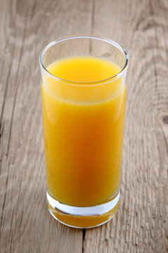 Glass of orange juice on old wooden table