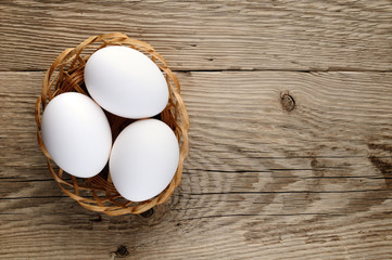 White eggs in basket on wooden background