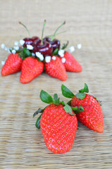 Strawberries and cherries on a mat background