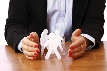 Female hands taking care of paper people on the desk