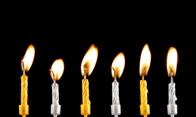 Golden and silver burning candles on black background