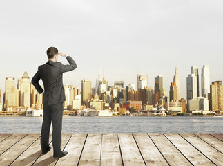Businessman standing on pier and modern city