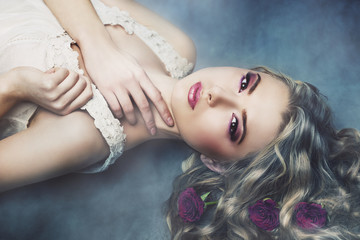 Naklejka premium Studio portrait of beautiful woman with roses in the smoke