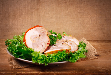 Smoked chicken roulade with salad, on a wooden surface