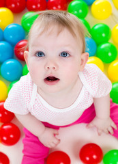 Fototapeta na wymiar Portret zabawne dziecko grając między kolorowymi kulkami