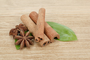 Star Anise, cinnamon and and green leave on wood