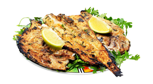 Grilled fish with greens on the plate - isolated obn white backg