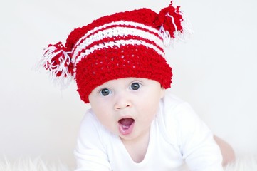 Portrait of the yawning baby in a red knitted hat