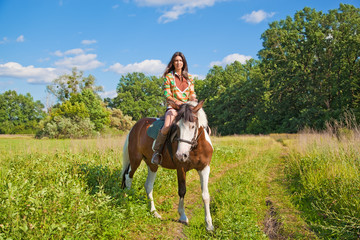 A young girl dressed as an Indian rides a paint horse