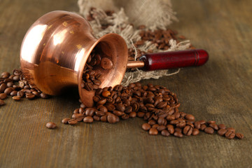 Coffee pot with coffee beans on wooden background