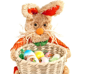 basket of easter eggs and toy rabbit on white background