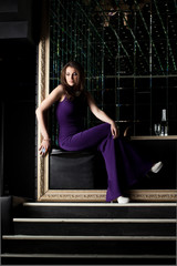 Sexy woman sitting in purple long dress