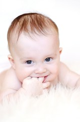 Smiling baby holds finger in mouth