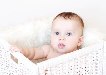 The baby sits in white basket