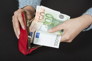 Woman's hands holding red purse and Euro banknotes
