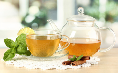 Cup of tea with mint,lime and cinnamon on table in room