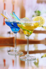 Yellow and blue cocktails in glasses on room background