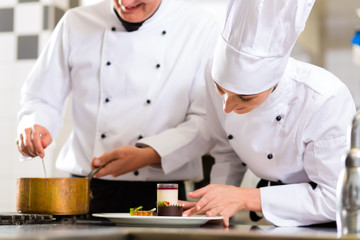 Chef team in restaurant kitchen with dessert
