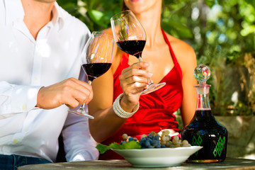 Woman and man in vineyard drinking wine