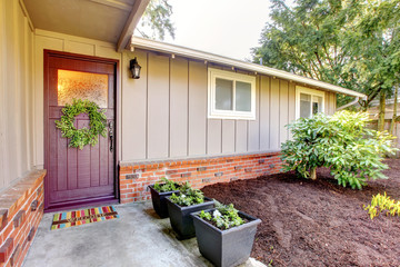 Brown grey house exterior with front door and spring landscape.