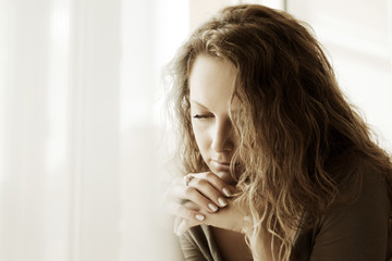 Fototapeta premium Sad woman against a window
