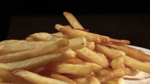 The plate with French fries rotates. Horizontal close up  view