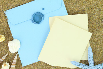 Paper card and blue envelope on the beach