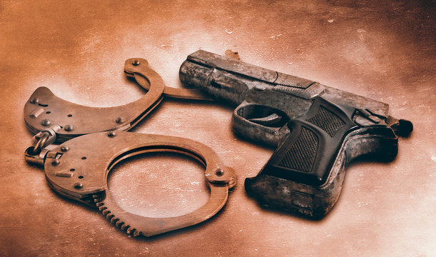 Gun and handcuffs on table. Photo in old color image style