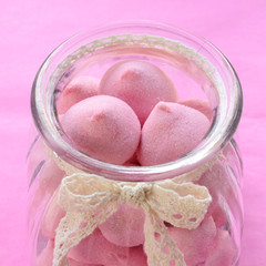 Pink marshmallow in glass jar on pink background