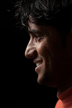 Portrait of young Indian man smiling over dark