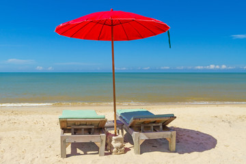 Red parasol with deckchair on tropical beach in Thailand