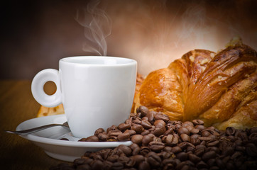 Coffee smoking on the coffee beans and croissant background