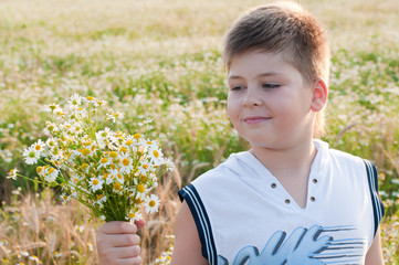 A boy with a bouquet of daisies in a field