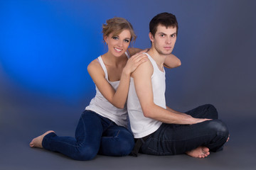 Fototapeta na wymiar young beautiful couple sitting over blue