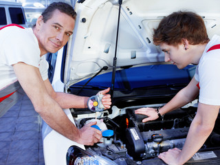 Two motor mechanics fixing the engine of a car in a garage