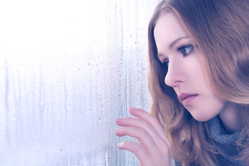 sadness girl at the window in the rain