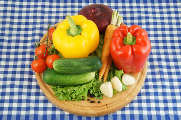 Vegetables on wooden cutting board on tablecloth
