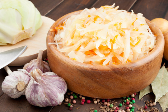 Sauerkraut with carrot in wooden bowl, garlic, spices, cabbage o