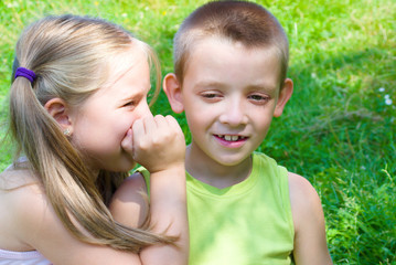 Little girl whispering something to her brother