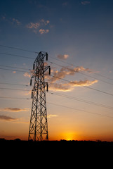 Electricity pylon against orange sunset