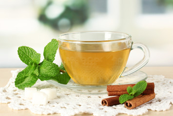 Cup of tea with mint and cinnamon on table in room