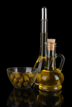 Different types of oil with olives on dark background